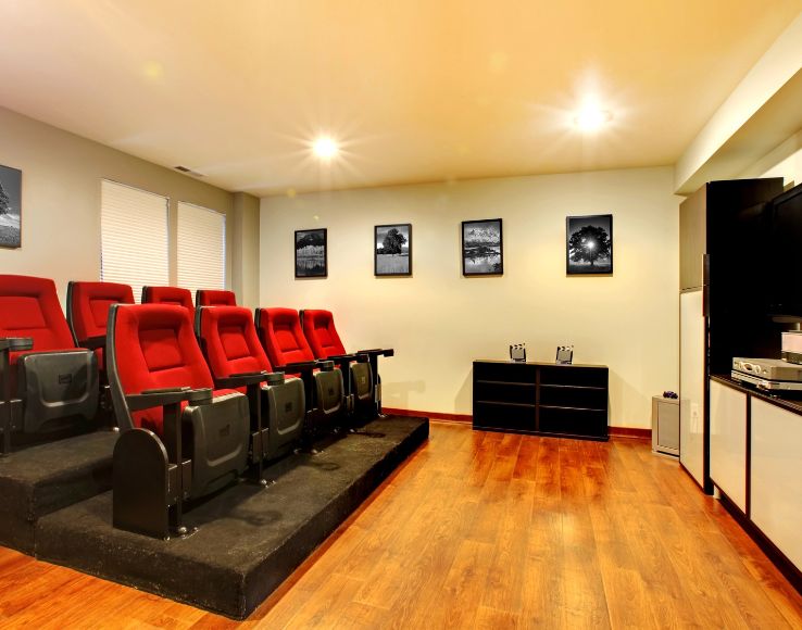 Home movie theater design with tiered red cinema seating in Millburn