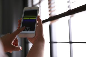 Controlling smart home blinds with a phone app at a window in Wyckoff