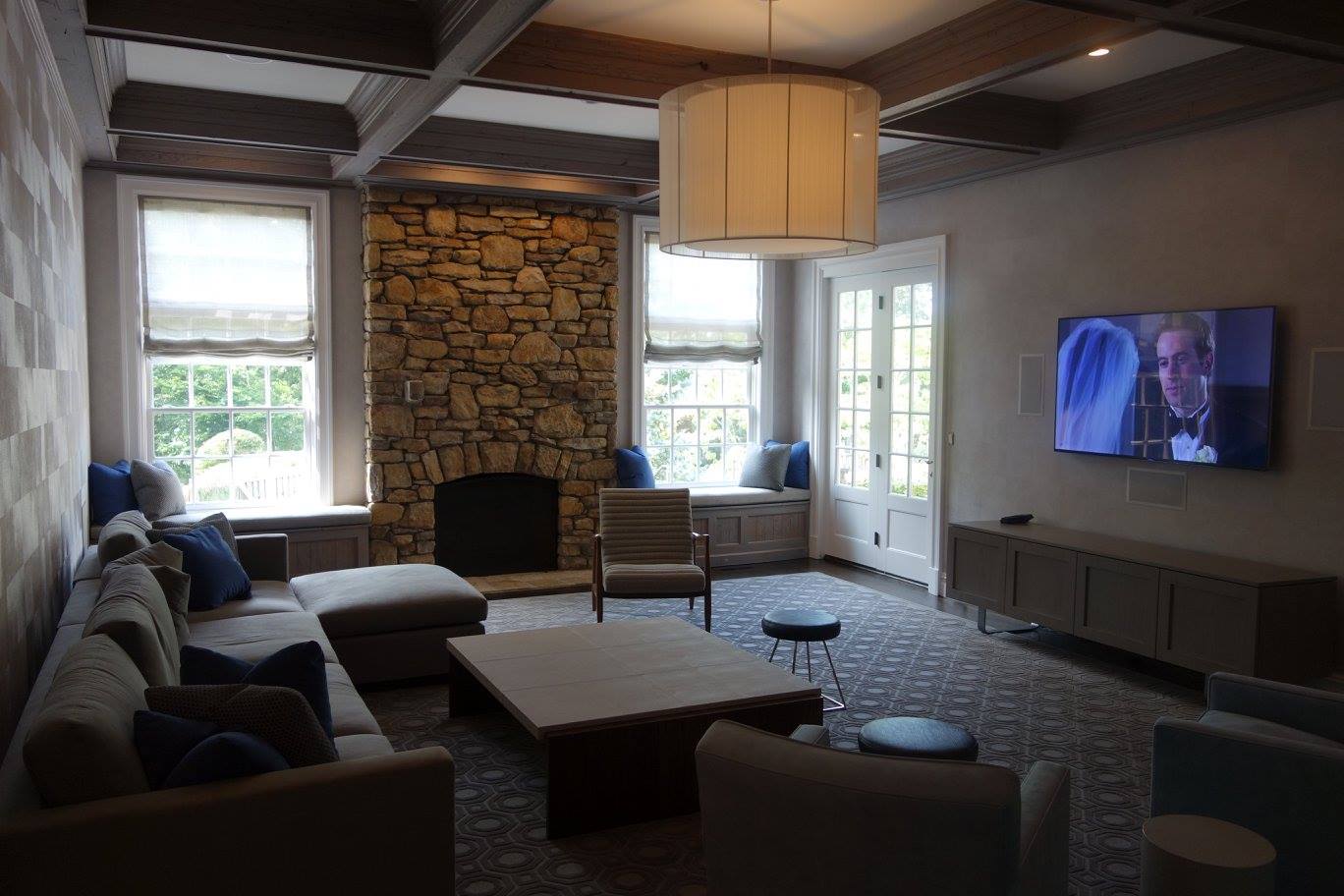Living room with a stone fireplace and a wall-mounted TV for a home A/V installation in Alpine