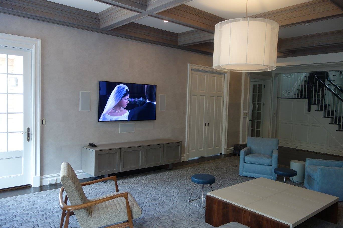 Living room home theater with a large wall-mounted TV and whole home audio in Alpine