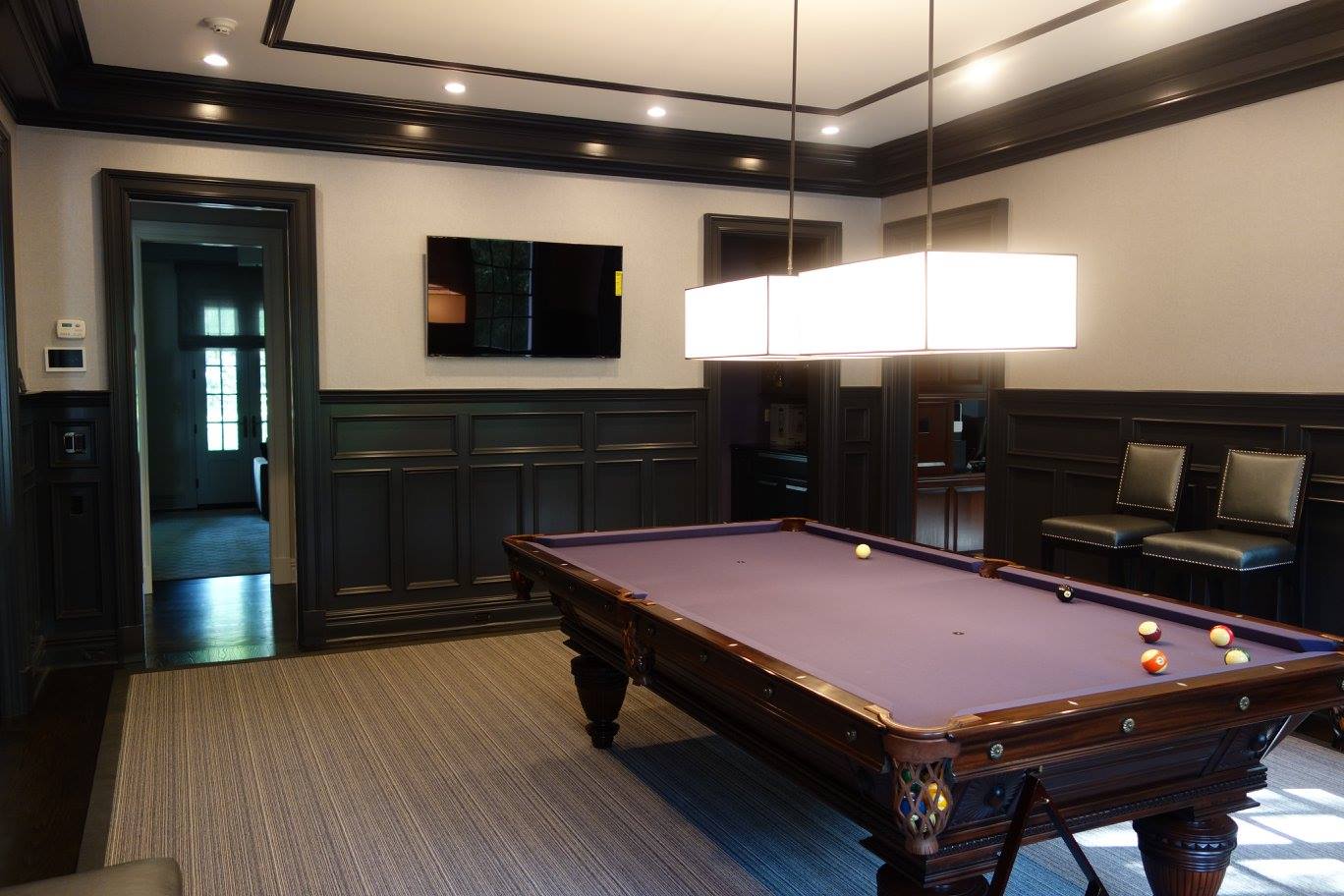 Billiards room with a pool table and a wall-mounted TV for a home A/V installation in Alpine