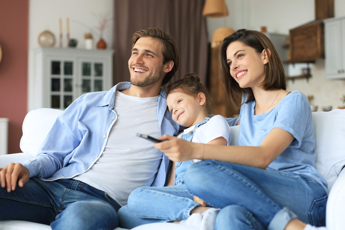 Family using a Control4 Systems home automation remote on a living room sofa in Wyckoff
