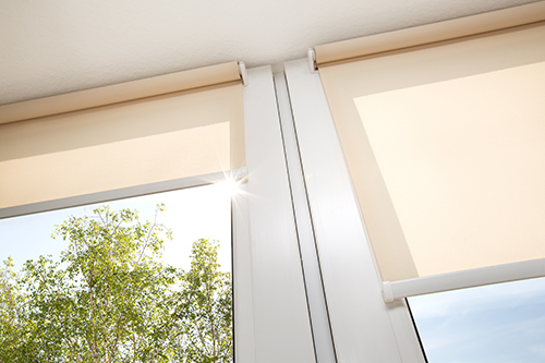 Electric blinds as roller shades on bright living room windows in New City