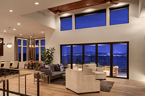 Smart home lighting in a great room with floor-to-ceiling windows at dusk in Saddle River