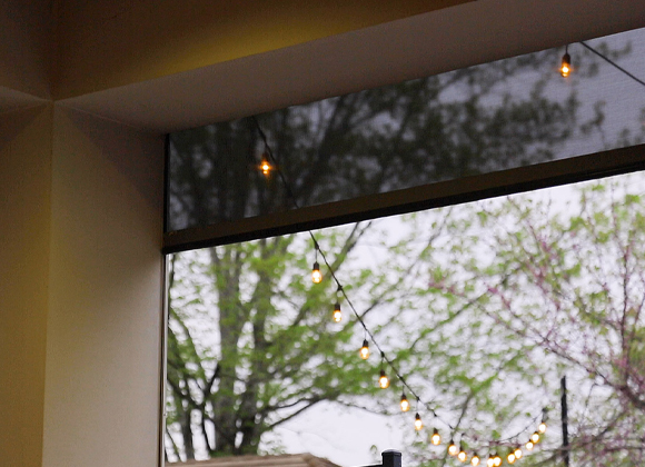 Window with sheer automatic shades raised over a garden view with motorized blinds in Wyckoff