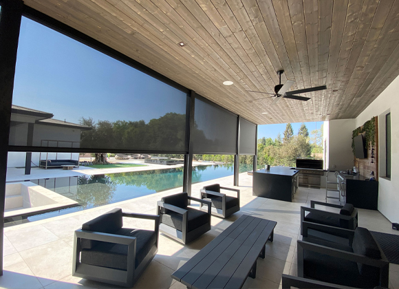Covered patio with motorized exterior shades and automated shades overlooking a pool in Saddle River