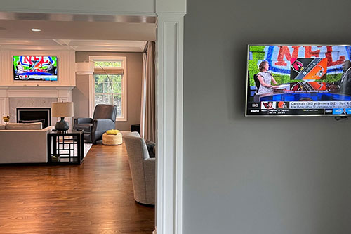 Adjoining rooms with wall-mounted TVs for a home audio and video installation in Chatham