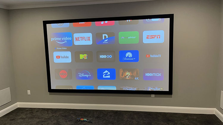 Home theater with a large projection screen showing streaming apps for a home theater installation in Englewood Cliffs