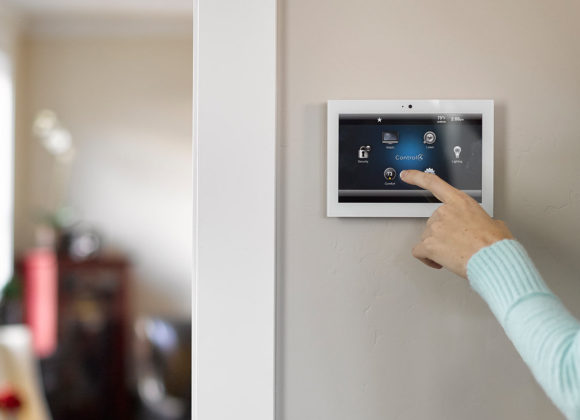 Pressing a wall-mounted Control4 Systems touchscreen for home automation in Wyckoff