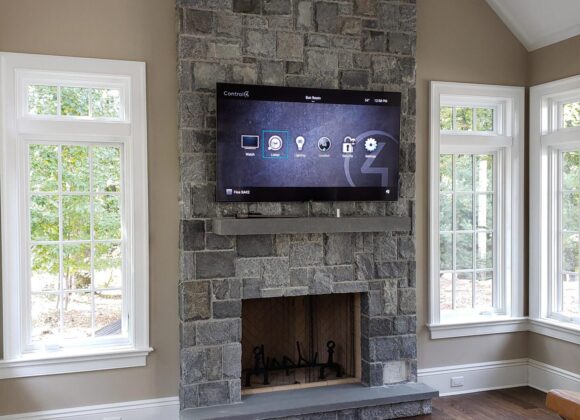 Control4 Systems automation interface on a TV above a stone fireplace in Saddle River