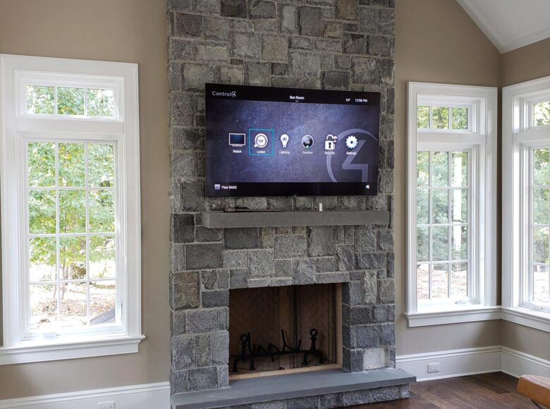 Control4 Systems automation interface on a TV above a stone fireplace in Saddle River