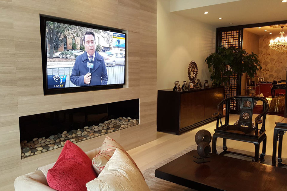 Living room with a wall-mounted TV above a linear fireplace for a home A/V installation in Tribeca