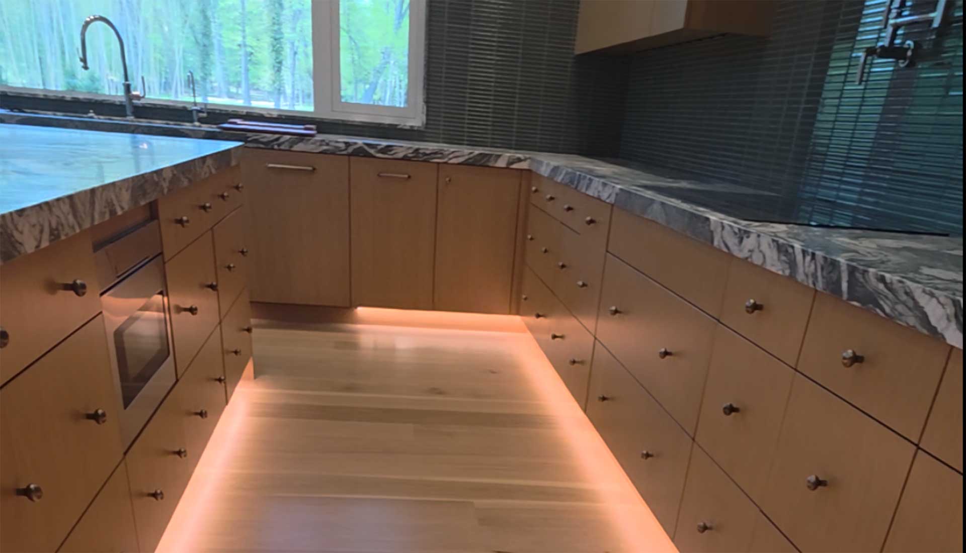 Modern kitchen with under-cabinet smart home lighting and motorized blinds in Rumson