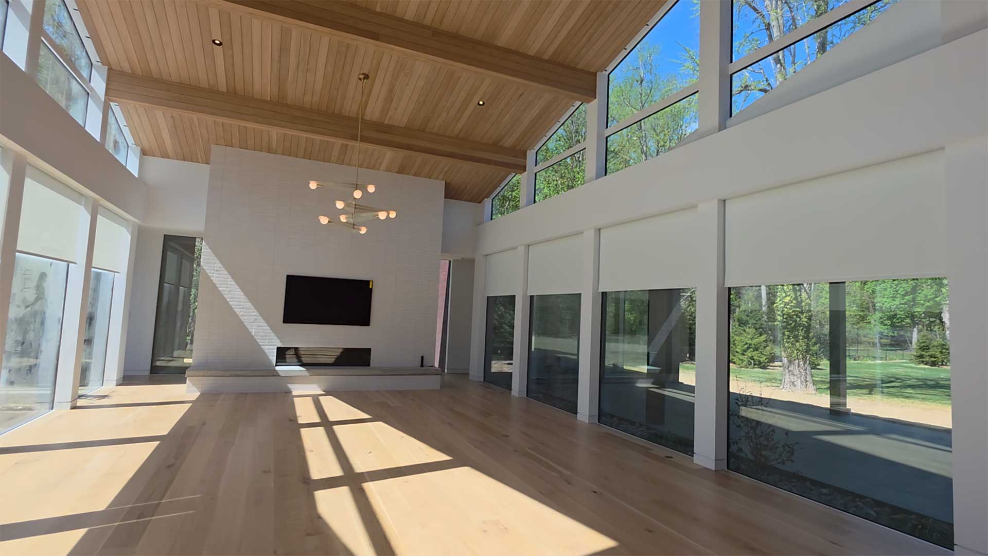 Modern great room with motorized shades and a wall-mounted home theater TV in Rumson